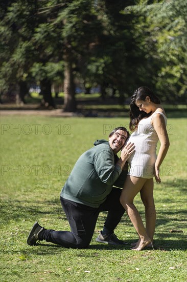 Man listening to his pregnant wife's tummy and smiling