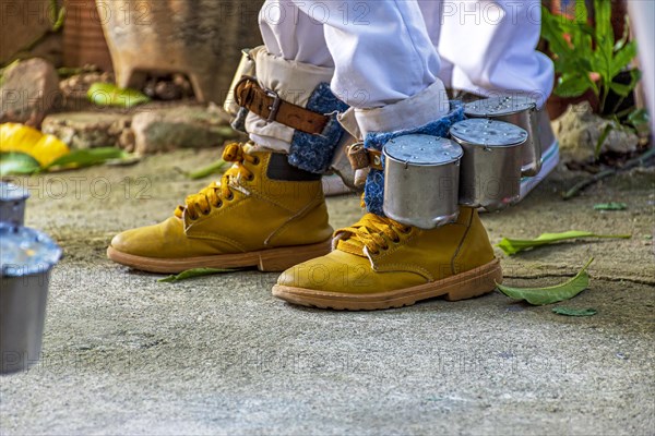 Curious percussion instrument used in some manifestations of popular culture in Brazil. With these rattles tied to their feet