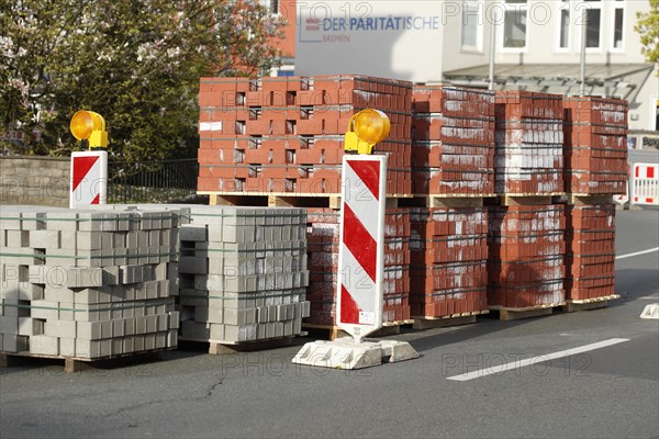 Stacked red building blocks with barrier beacons on a construction site for a cycle path