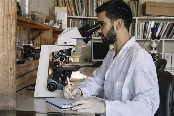 Male scientist looking under microscope