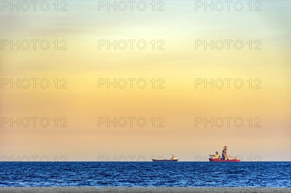 Ships on the horizon during tropical sunset at Copacabana beach in Rio de Janeiro