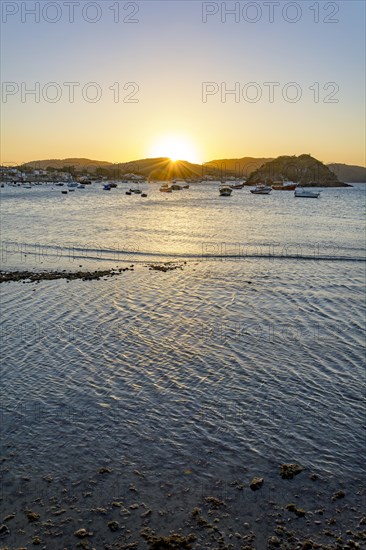 Sunset behind the hills and reflected in the sea waters of the city of Buzios on the north coast of Rio de Janeiro