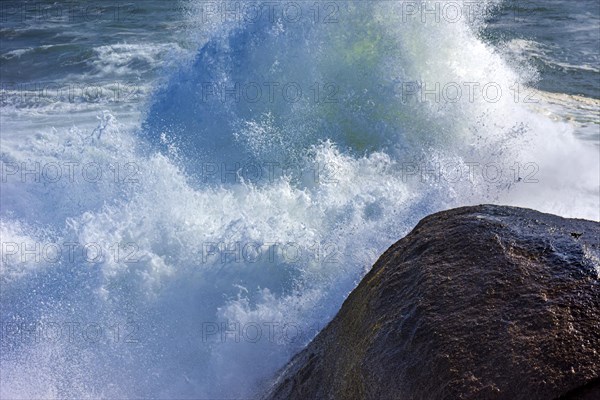 Stormy wave crashing against the rocks with sea water splashing in the air