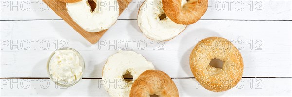 Bagel sandwich for breakfast topped with cream cheese on wooden board from above Panorama in Stuttgart