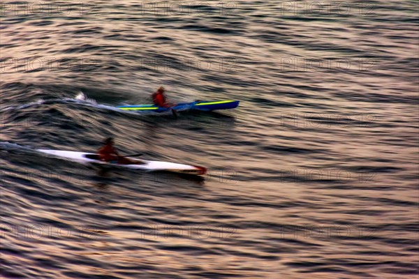 Canoeing at sunset in the sea of the city of Salvador in Bahia with blurred motion and unrecognizable people