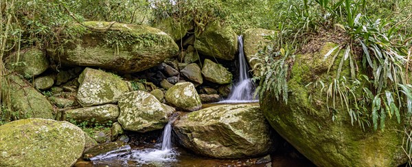 Small waterfall panoramic among the rainforest vegetation of Ilhabela island with mossy stones on the north coast of Sao Paulo state