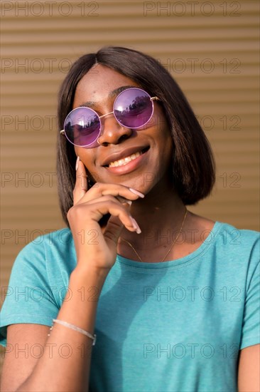 Capturing the Essence of Summer: A Portrait of a Young African American Tourist in a Green T-Shirt and Shades Against a Brown Wall