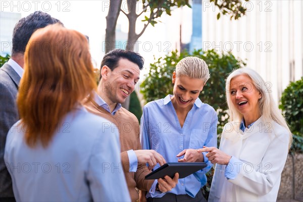 Cheerful group of coworkers laughing and having fun outdoors in a corporate office area