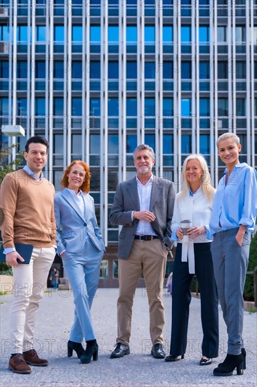 Portrait of cheerful group of coworkers walking outdoors in a corporate office area