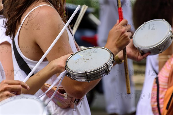 Woman playing tambourine in crowded brazilian streets during carnival festivities