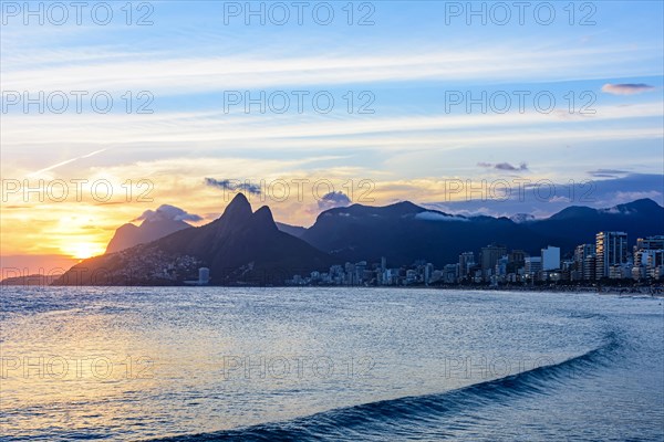 Sunset behind the mountains of the city of Rio de Janeiro on Ipanema beach