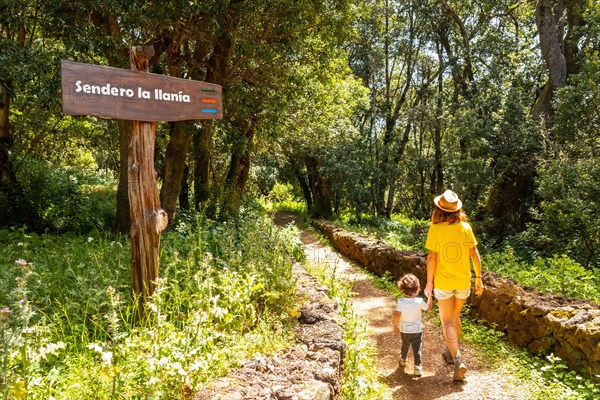 A mother with her son next to a sign identifying the La Llania trekking trail in El Hierro