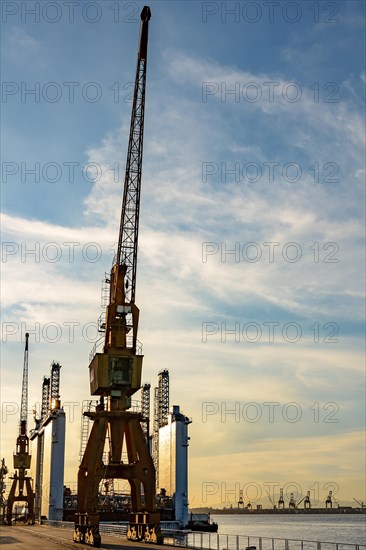 Several cranes and the view of the pier in the port of Rio de Janeiro during sunset.