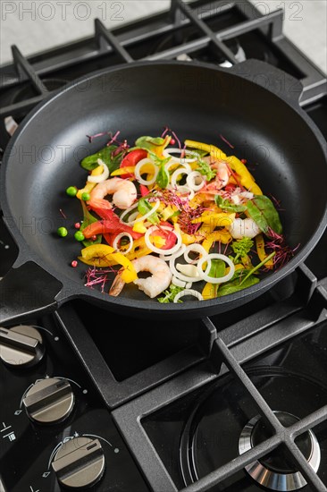 Frying fresh vegetables and shrimps in a frying pan