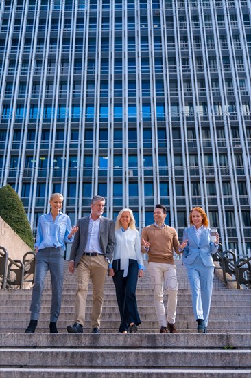 Cheerful group of coworkers outdoors in a corporate office area going down some stairs going to work