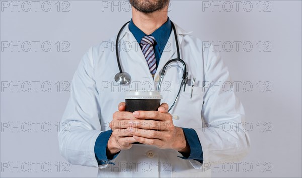 Young doctor holding a coffee to go isolated. Doctor hands holding paper coffee. Doctor holding takeaway coffee on isolated background