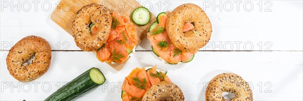 Bagel sandwich for breakfast topped with salmon fish from above on a wooden board Panorama in Stuttgart