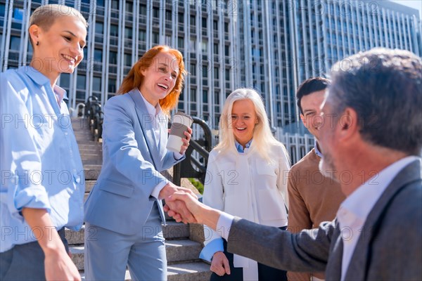 Greeting and shaking hands coworker. Group of executives or business people outdoors in a corporate office area