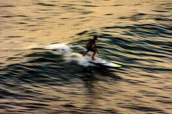 Stand up paddle at sunset in the sea of the city of Salvador in Bahia with blurred motion and unrecognizable people