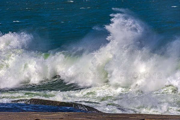 Strong waves crashing against rocks during storm on a sunny day