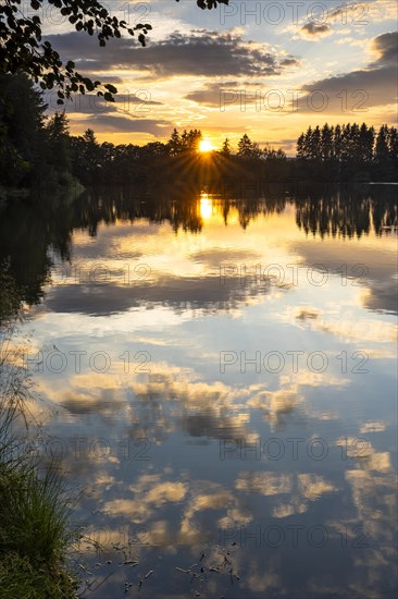 The Postfelden reservoir at sunset. Clouds are reflected in the calm water. Hoellbachtal