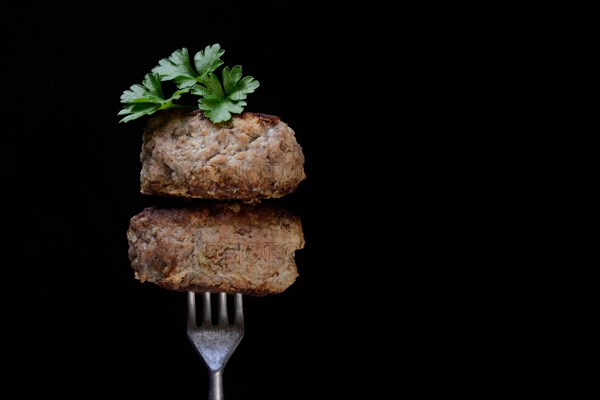 Two homemade meatballs on fork