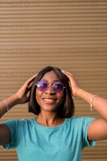 A Portrait of a Young African American Tourist in a Green T-Shirt and Shades Against a Warm Brown Wall