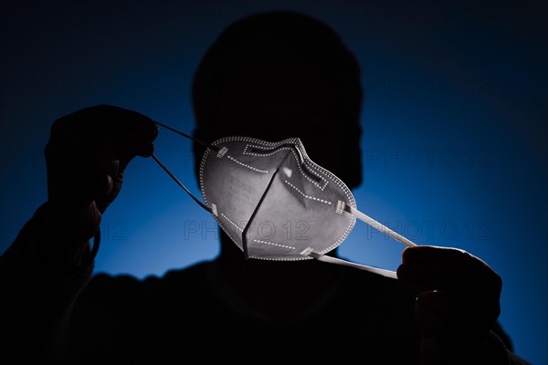 A man holds an FFP2 protective mask in front of his face. Berlin