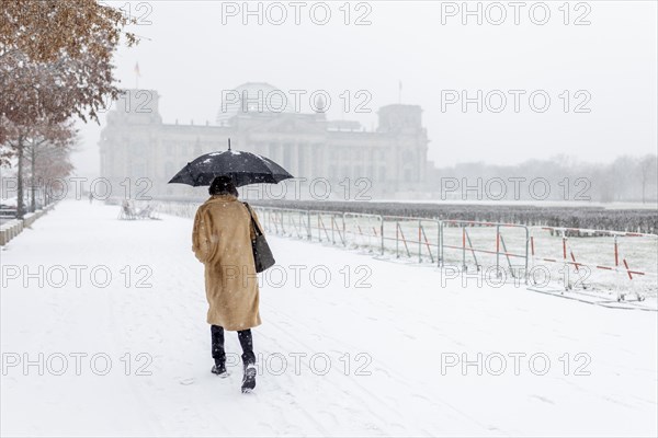 A person stands in front of the Bundestag in the driving snow in Berlin