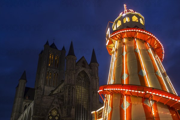 Illuminated helter skelter at evening Christmas market and the Saint Nicholas church