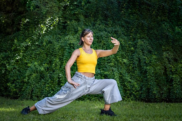 Woman practicing tai chi outdoors. Woman combines the practice of Chi Kung and Chinese martial arts in a natural setting to enhance his practice and his connection to the energy of nature