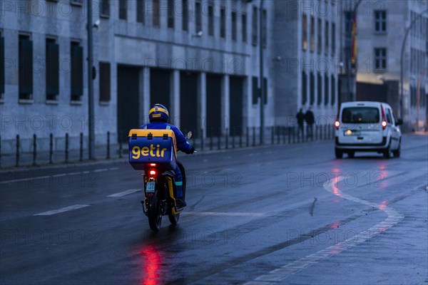 An employee of the delivery service Getir drives along Wilhemstrasse in the evening in Berlin