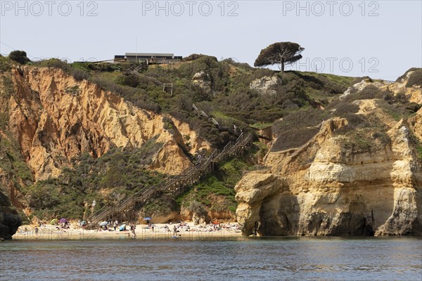 Wooden steps leading to the sandy beach of Praia do Camilo on the rocky coast of Lagos