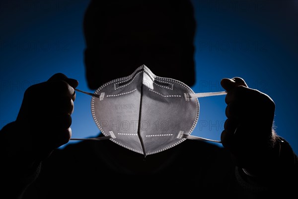 A man holds an FFP2 protective mask in front of his face. Berlin