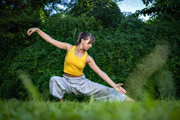 Young Woman practicing tai chi chuan in nature. Chinese management skill Qi's energy