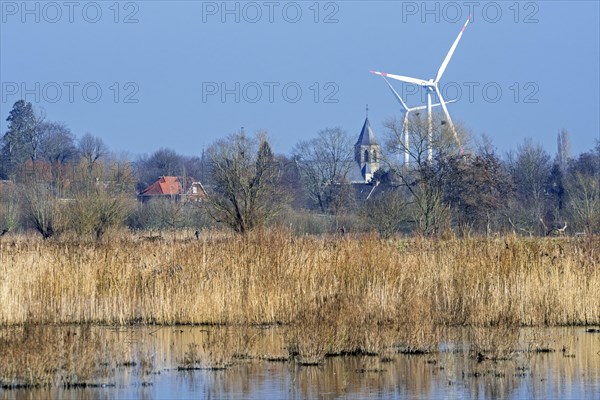 Church tower of the village Mariakerke near Ghent and wind turbines seen from nature reserve Bourgoyen-Ossemeersen in winter