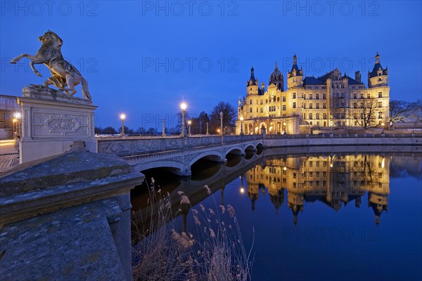 Illuminated Schwerin Castle with the castle bridge to the castle island in the evening