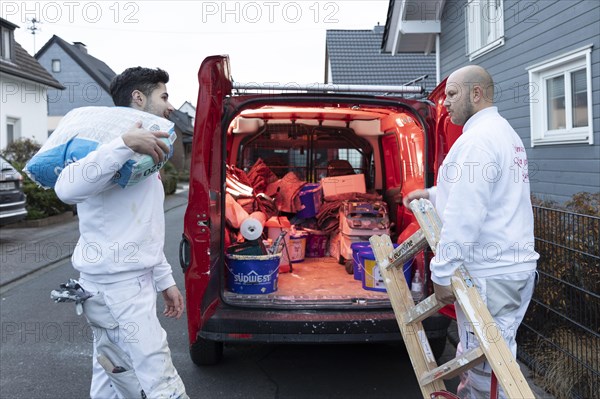 Subject: Master painter and apprentice loading a van with work materials