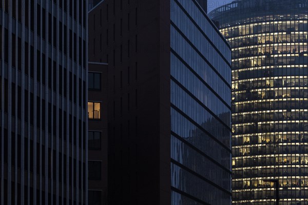 Illuminated windows in office buildings stand out at blue hour in Berlin