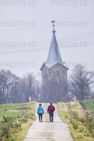 Two people walking along a path to a church in Kunnerwitz