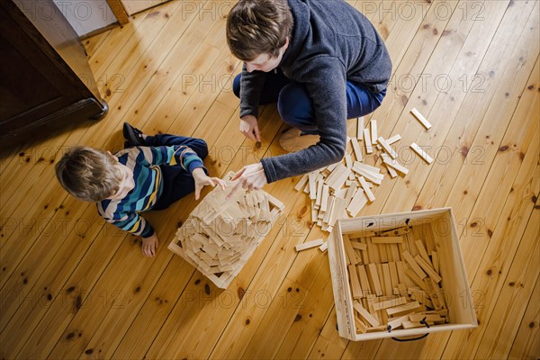 Symbolic photo on the subject of creative play among children. A boy builds with wooden building blocks with an adult. Berlin