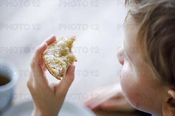 Symbolic photo on the topic of nutrition in children. A boy holds a roll or bread in his hand. Berlin