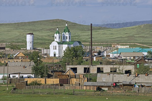 Typical white Orthodox church with green roof in little village in rural Southern Siberia