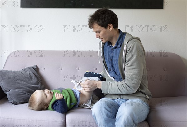 Subject: Father swaddles a child aged nine months with cloth nappies