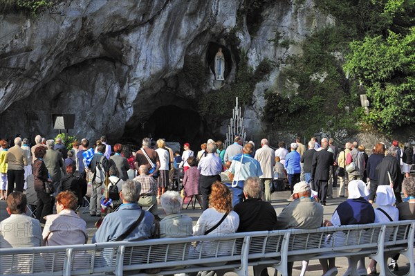 Pilgrims praying in front of the grotto at the Sanctuary of Our Lady of Lourdes