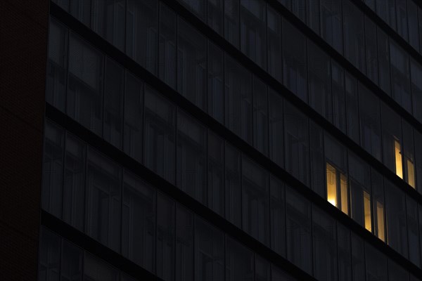 Illuminated windows in office buildings stand out at blue hour in Berlin