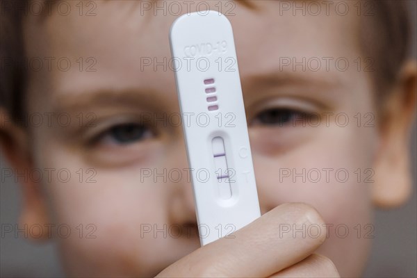 A child holds a positive SARS-CoV-2 Rapid Ag Antigen rapid test. Berlin