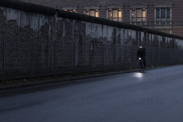 A cyclist stands out in front of the Berlin Wall in Berlin