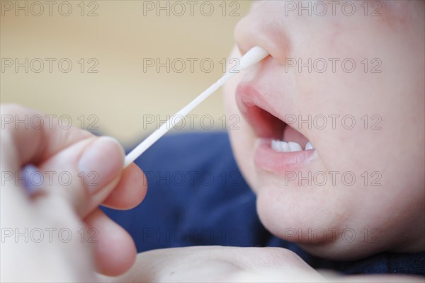 Symbolic photo on the subject of nasal testing for young children. A mother takes a swab from her child's nose. Berlin