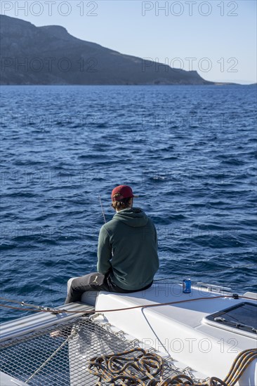 Young man fishing on a sailboat